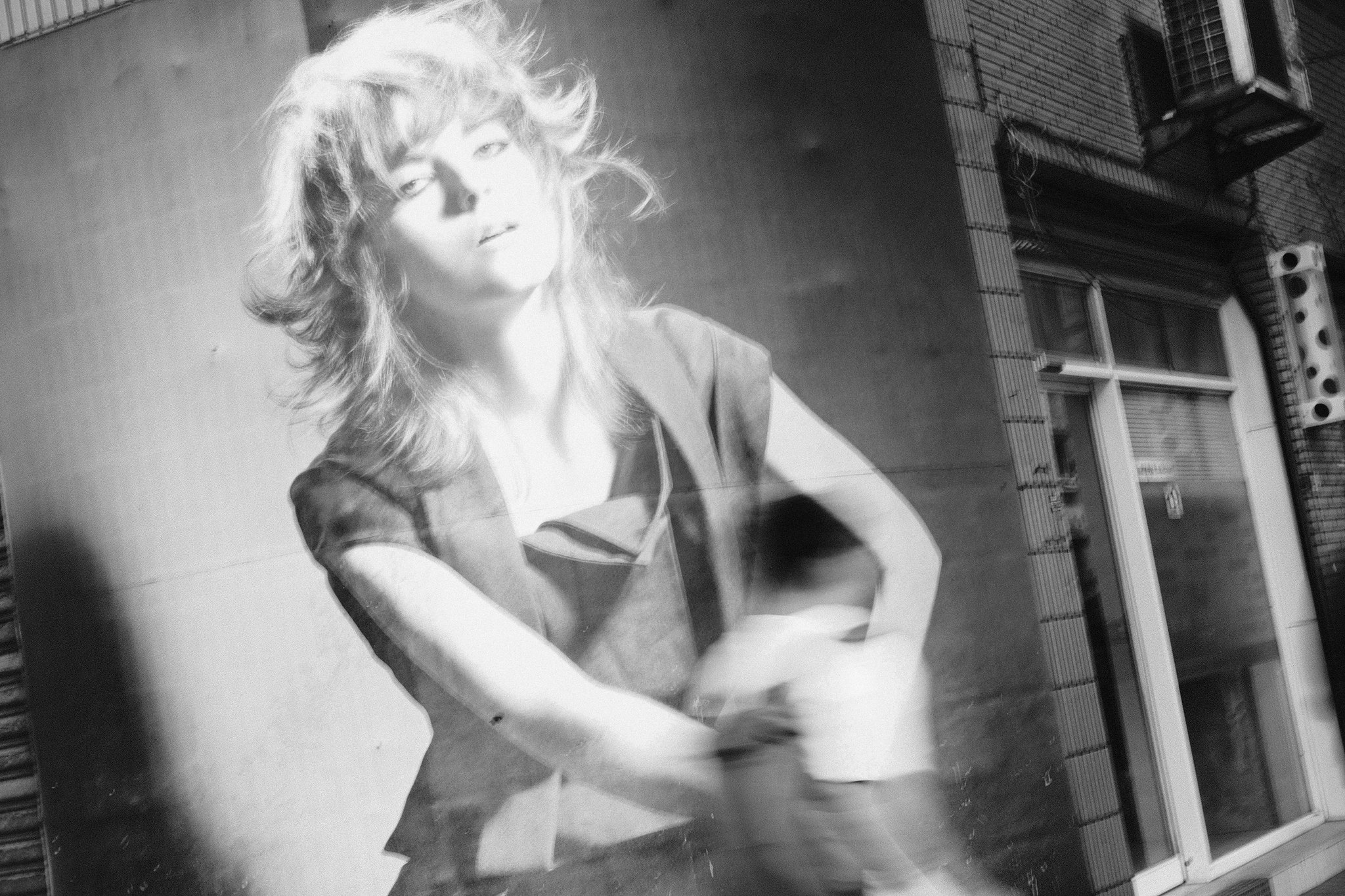 Blurred pedestrian passing a bright mannequin display in Taiwan street photography