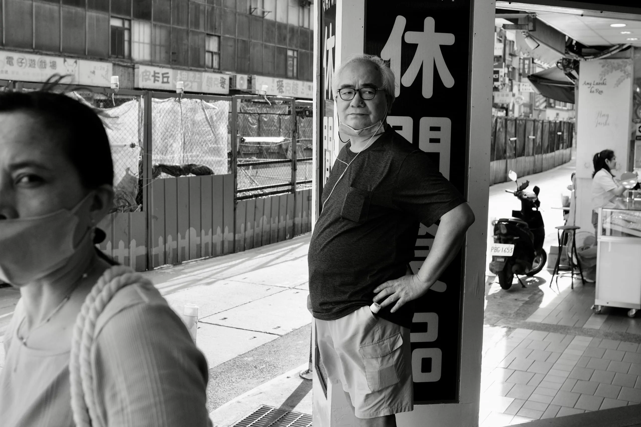 騎樓休閒招牌旁男子靠牆站著，前景女子半張臉經過，365 Project September 15