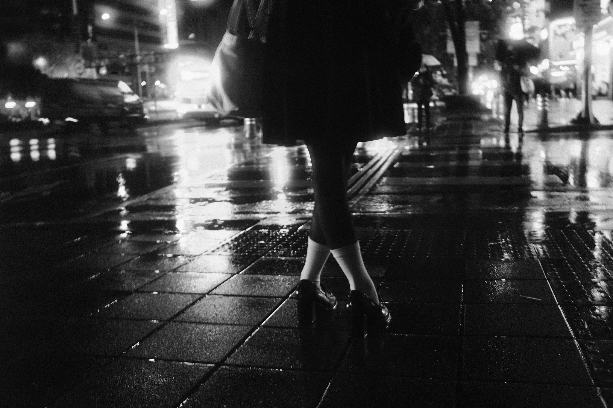 Atmospheric street scene in the rain with glowing urban lights and silhouettes